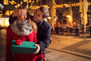 Man  keeps his girlfriend eyes covered while  she giving a gift , romantic surprise for Christmas