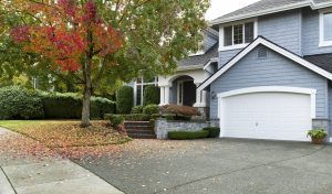 Driveway to front walkway view of partial front of residential home during early autumn season.