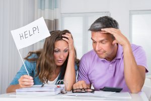 Worried Couple Sitting In Living Room Needs Help Due To Financial Crisis