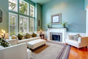 High ceiling aqua living room with white leather couch, ottaman, armchairs and fireplace