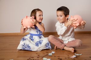Children sitting on the floor and holding their piggy bank