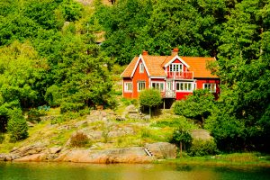 Askeron, Sweden - September 9, 2016: Environmental documentary of seaside home in woodland slope down to water.