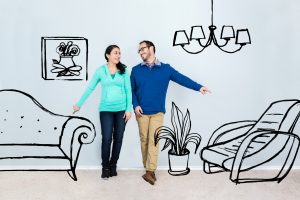 Mid adult Hispanic couple discuss where to put furniture in their new home. The both point in different directions in the emply living room. Custom artwork is digitally imposed on the photo. The artwork contains a sofa, chair, plant, lighting fixture and framed artwork.  Custom artwork copyright is wholly owned by Steve Debenport Imagery, Inc.