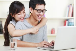 happy young couple using laptop at home