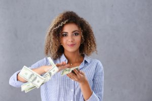Beautiful black woman portrait. Scattering money notes dollars in fashion vows style mulatto curly hair with white locks eye view of the camera