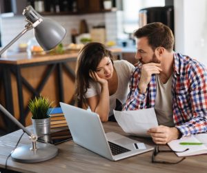 frustrated-couple-checking-bills-at-home-using-laptop-picture-id1179761508