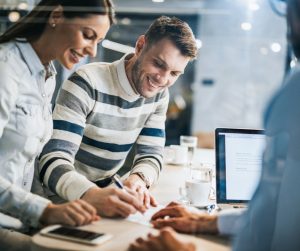 happy-couple-signing-a-contract-on-a-business-meeting-with-their-picture-id1142970162-1